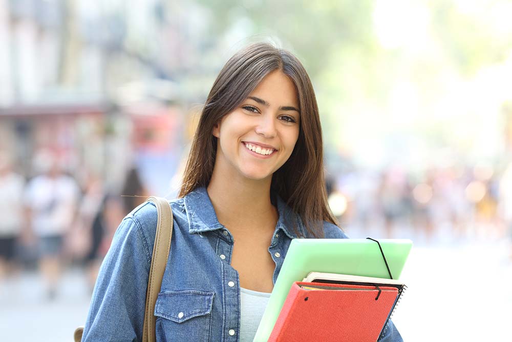 young college student holding books outside