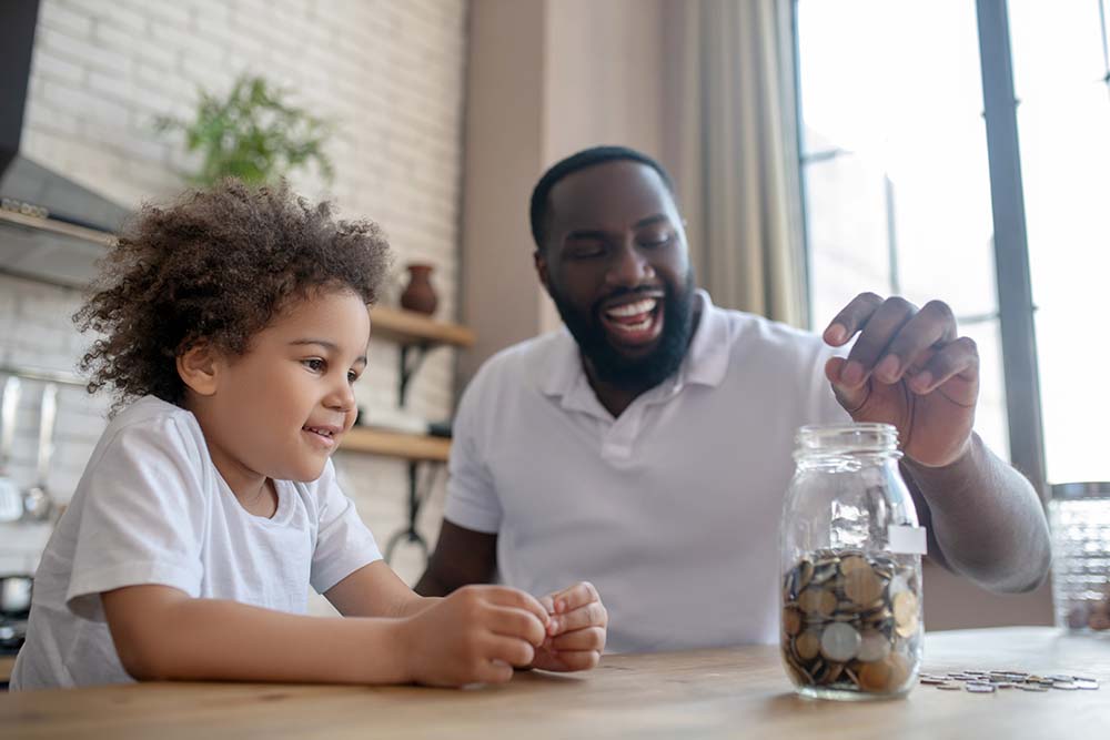 father and son saving loose change in a jar