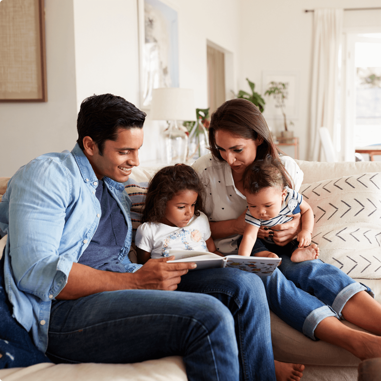 Family of four reading a book together on the couch