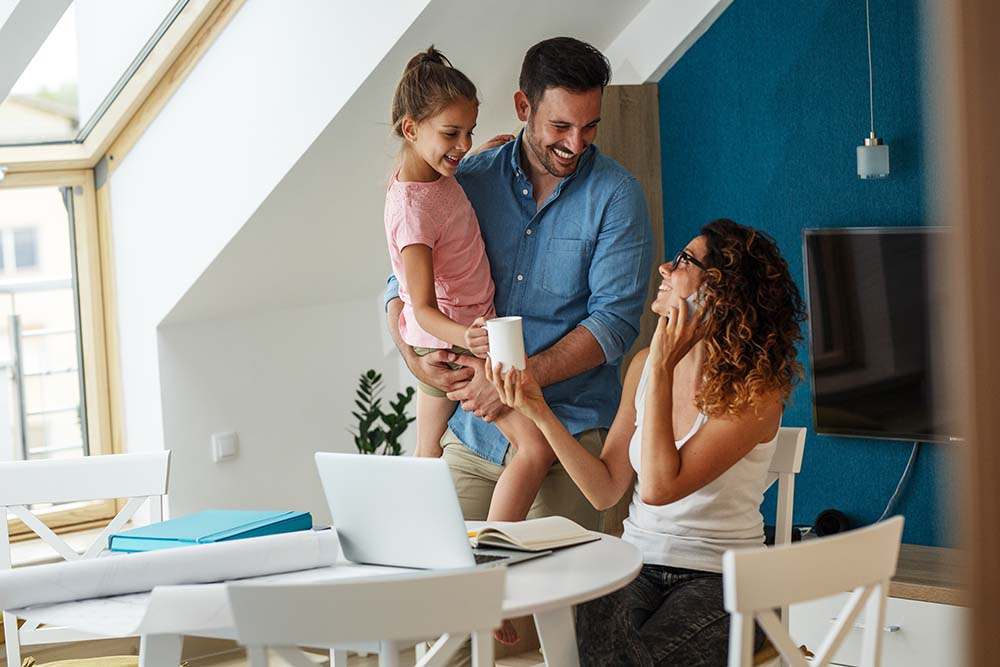 family smiling at each other while woman works on computer and talks on phone