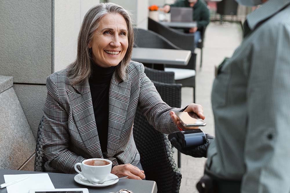 elderly woman using digital wallet to pay for coffee